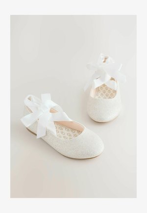 Bailarinas blancas con purpurina, punta redonda, cintas al tobillo y una plantilla rosa suave con un estampado floral. Suela plana de goma.