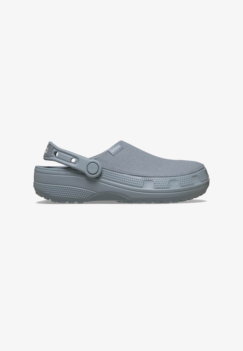 Sabot Crocs gris clair à enfiler avec une tige en mesh respirant et une sangle de talon réglable, présenté en profil latéral sur fond blanc.