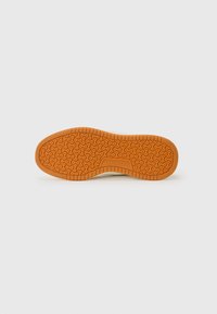 Semelle de chaussure avec une surface en caoutchouc orange texturé. Présente un motif ondulé et un logo "Skechers" au centre. Bords lisses.