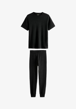 Schwarzes, geripptes Kurzarm-T-Shirt und passende schwarze Slim-Fit-Hosen. Beide aus weichem Stoff, mit glatter Textur und tailliertem Design.