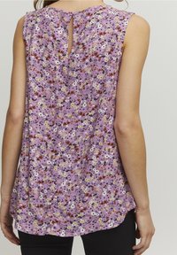 Blomstret ærmeløs top i lavendel med en nøglehulryg, der har en række små, flerfarvede blomster og en blød tekstur.