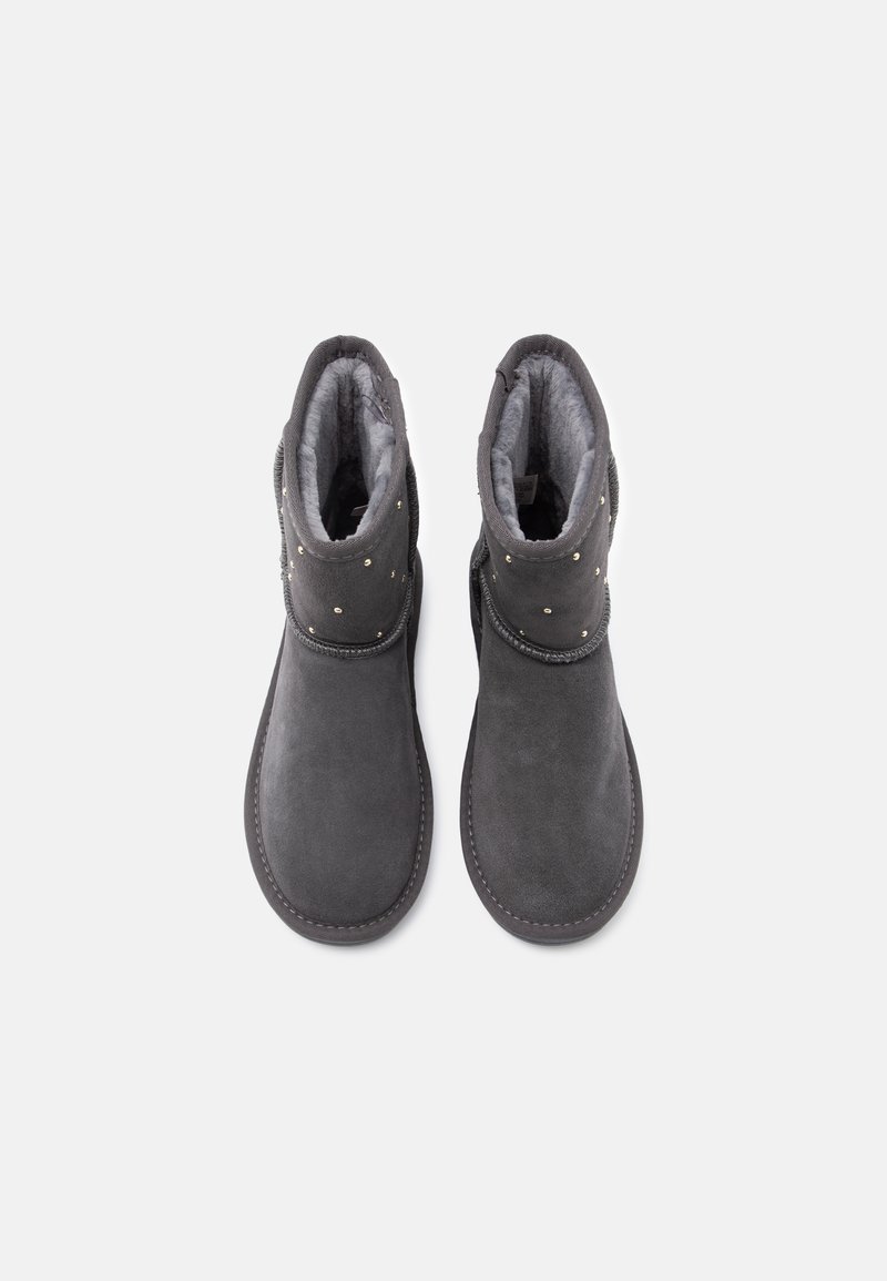 Graue Knöchelstiefel mit einer weichen Textur, ausgestattet mit einem flauschigen Futter und dekorativen Nieten auf der Oberseite. Runde Zehenform und genähte Sohle.