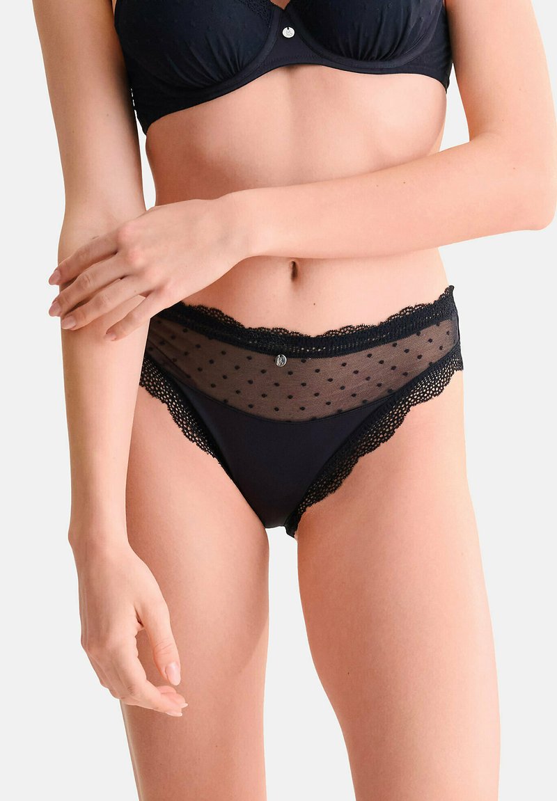 Sous-vêtements noirs avec des bordures en dentelle et un panneau en maille transparente à pois à l'avant. Matériau doux, présentant une taille festonnée et un petit accent métallique.