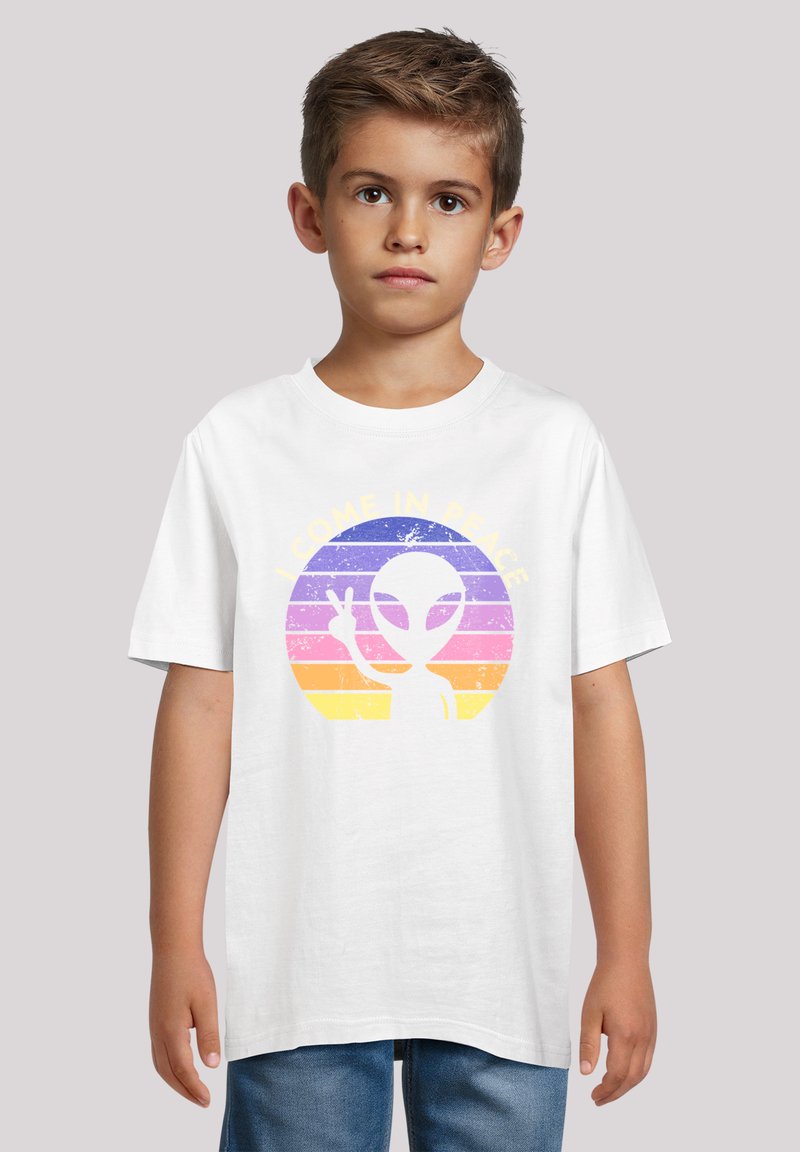 Weißes Baumwoll-T-Shirt mit einem retro-alien Grafik und dem Text "I COME IN PEACE" in Gelb, vor einem mehrfarbigen gestreiften Hintergrund.