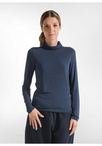 Bluză lungă cu mâneci dintr-un material moale și ușor, de culoare bleumarin, cu guler cowl. Are o croială slim și o textură netedă. Asortată cu o piesă de jos închisă la culoare.