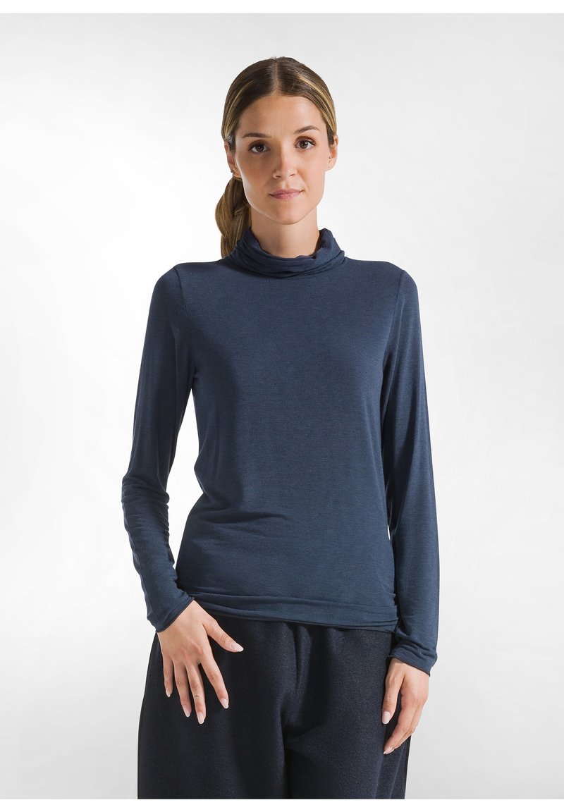 Bluză lungă cu mâneci dintr-un material moale și ușor, de culoare bleumarin, cu guler cowl. Are o croială slim și o textură netedă. Asortată cu o piesă de jos închisă la culoare.