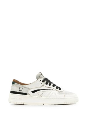 Sneaker bianca basse con lacci neri, striscia laterale nera, tallone in pelle scamosciata beige e suola spessa in gomma bianca.
