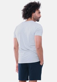 Graues T-Shirt mit kurzen Ärmeln und Rundhalsausschnitt, kombiniert mit dunkelblauen Shorts. Der Stoff wirkt weich und mit einer glatten Textur.