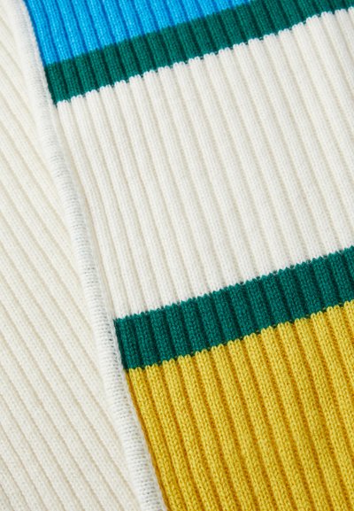 Gros plan sur un tissu en tricot côtelé avec des rayures horizontales de couleurs bleu, vert, blanc et jaune.