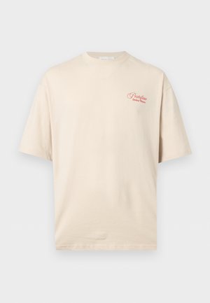 Beige T-skjorte med korte ermer, rød tekst "Portofino Dolce Mare" på øvre venstre bryst, rund hals og ledig passform.