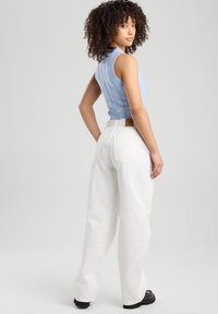 Light blue ribbed tank top paired with white wide-leg jeans. Notable details include back pockets and a brown leather tag on the waistband.