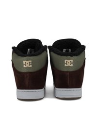 Baskets montantes en suède marron et textile vert avec doublure en polaire noire, semelle en caoutchouc grise et logo embossé sur le talon.