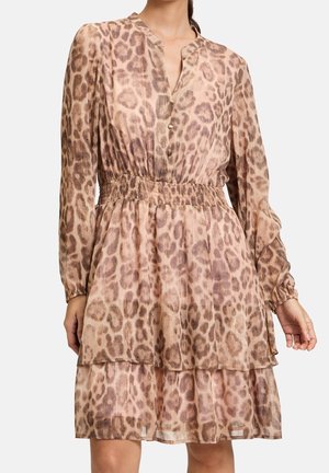 Langärmliges, gestuftes Kleid mit Leopardenmuster, elastischem Taillenbund und teilweiser Knopfleiste vorne, getragen von einer Person von Hals bis über die Knie.