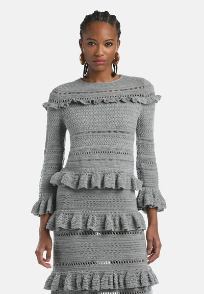 Szara sukienka na szydełku z długimi rękawami, falbaniastymi akcentami przy dekolcie i na brzegu, teksturowanym wzorem z poziomymi paskami i ażurowymi detalami.