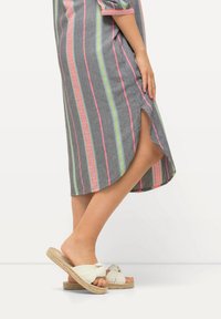 Vestido a rayas gris con líneas rosas, verdes y naranjas; hasta la rodilla con una abertura lateral. Sandalias de esparto blancas con detalle plisado.