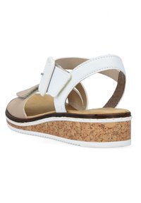 Beżowe i białe sandały na korkowej platformie, z rzepem i regulowanym zapięciem. Otwarty tył i minimalna tekstura.