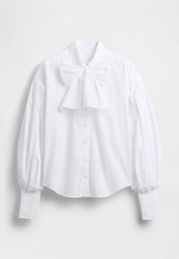 Bela bombažna srajca z veliko pentljo na ovratniku, nabranimi rokavi in sprednjim srajčnim zapenjanjem na gumbe. Gladek tekstura, širok kroj in ukrivljen rob.