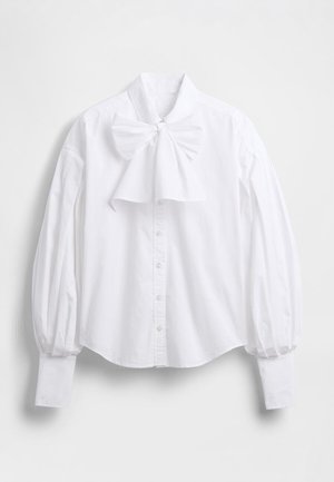 Witte katoenen blouse met een grote strik bij de kraag, opgeblazen mouwen en knoopsluiting aan de voorkant. Soepele textuur, losse pasvorm en afgeronde zoom.