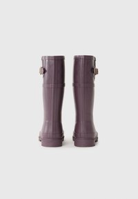 Bottes de pluie en caoutchouc violet avec une texture lisse, des rainures horizontales et un accent de boucle décorative à l'arrière.