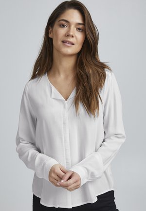 White long-sleeve shirt with a V-neck, made of smooth fabric, featuring a front button closure and rounded hemline.