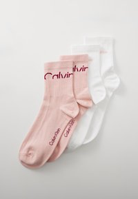 Kaks paari Calvin Kleini lühikeste sukkade, üks roosa punase logoga ja teine valge helesinise logoga, asetatud üksteise peale valgel taustal.