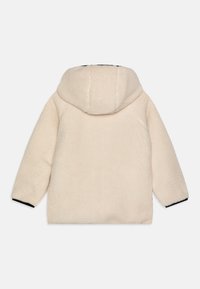 Cremefarbenes Fleece-Jackett mit Kapuze, langen Ärmeln und schwarzen Akzenten an den Bündchen. Weicher Stoff mit lockerer Passform und minimaler Detailgestaltung.