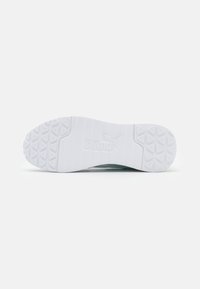 White rubber sole of a Puma shoe showing triangular tread patterns and the embossed Puma logo at the center.