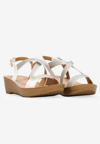 Sandali wedge bianchi con cinturini incrociati caratterizzati da dettagli in rete argentata. Intersuola morbida e testurizzata e suola in gomma resistente con grip.