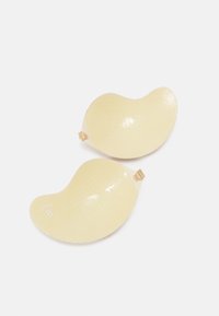 Silicone adhesive bra cups in light beige, shaped like a curved “B,” with a textured surface and adjustable clips for secure fit.