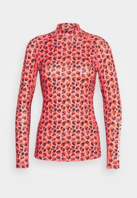 Long-sleeve, mock-neck top in sheer, stretchy fabric featuring a coral base with black and orange leopard spots; branded accent on the sleeve.