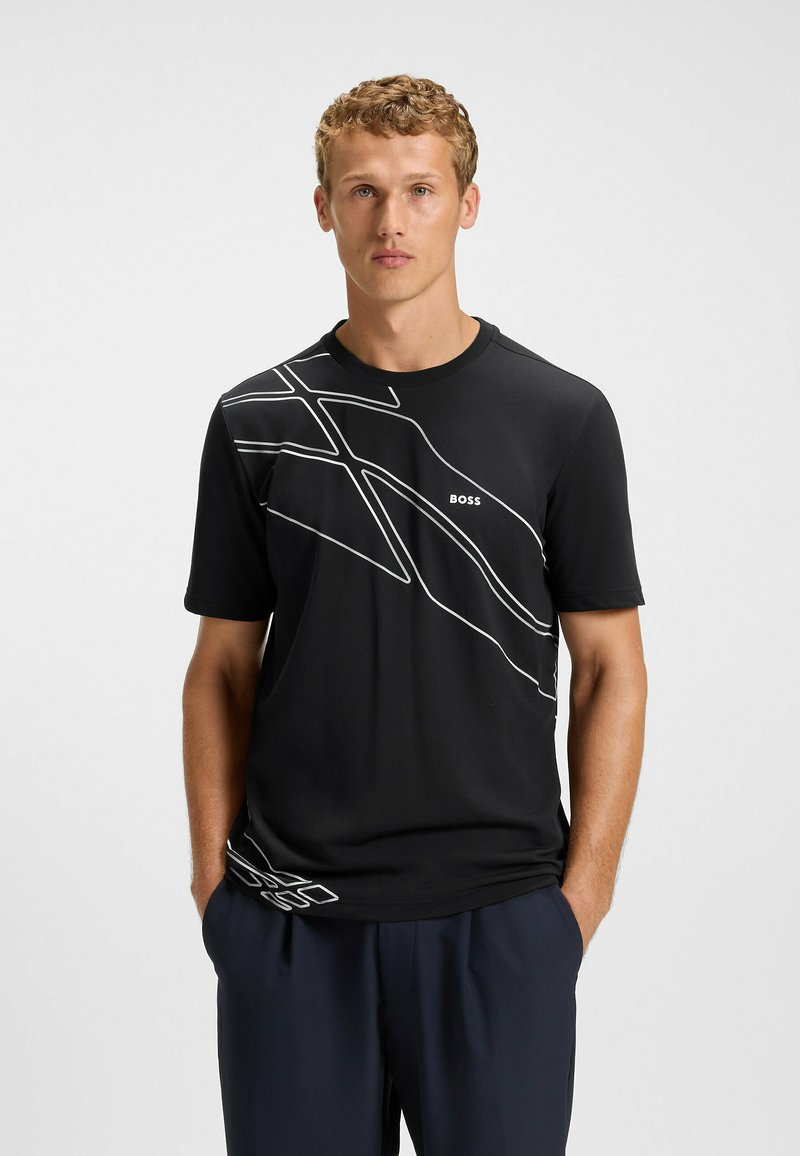 Sort t-shirt med kortærmer, der har et hvidt abstrakt linjemønster på tværs af brystet, lavet af et glat og let stof.