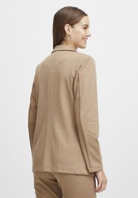 Top de manga larga color marrón claro con cuello, de corte recto, textura suave y costuras en la parte trasera.