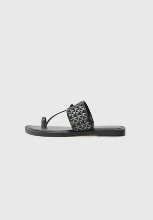 Schwarze Flip-Flop-Sandale mit einem gemusterten Riemen, ausgestattet mit einem Zehensteg und einer flachen Sohle. Der Riemen hat ein geometrisches Design in Grau.