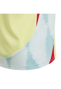 Short-sleeve athletic shirt in yellow, featuring blue and red accents with a wavy pattern. Made from lightweight, textured fabric.