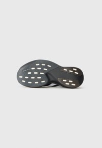 Semelle de chaussure noire avec des motifs de grip rectangulaires blancs et le logo Continental sur un fond blanc uni.