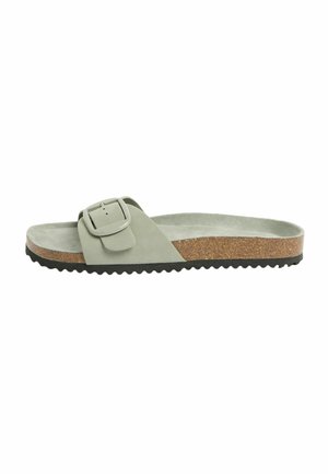 Slip-on sandal with light green suede strap, large buckle, cork footbed, and black ridged sole.