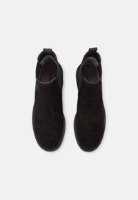 Svarta mockaankelhaka med elastiska sidor, rund tå och dragflik. Slät textur med en minimalistisk design och inga synliga mönster.