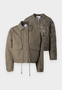 Due giacche in olive green: una è realizzata in un tessuto liscio con colletto a punta e due tasche frontali; l'altra è trapuntata con collo rotondo.