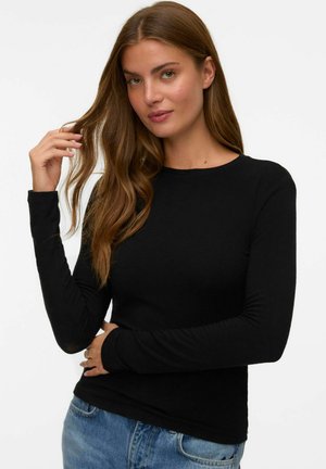 Zwarte lange mouwen shirt van zachte stof, met een ronde halslijn en een getailleerde pasvorm, gecombineerd met casual blauwe jeans.