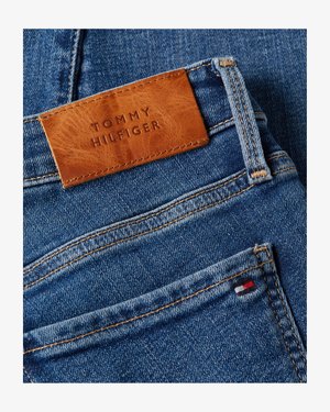 Vaqueros vaqueros azules con costuras naranjas, etiqueta de cuero marrón Tommy Hilfiger y pequeño logotipo de tela rojo, blanco y azul en el bolsillo trasero.