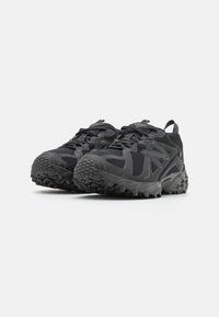 Black athletic shoes feature a mesh upper with textured accents, a sturdy rubber sole, and a rugged tread pattern for traction.