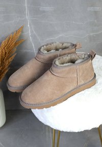 Botas de tobillo de ante color tostado con forro de suave piel de peluche, punta redonda, detalles de costura, tira en la parte trasera y suela de goma.