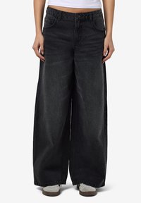 Zwarte wijde spijkerbroek met een hoge taille, twee voorzakken en een knoopsluiting. Gemaakt van denim met een vervaagde afwerking en een losse pasvorm.