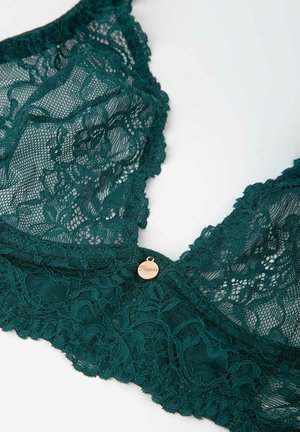 Błękitny koronkowy biustonosz z misternym kwiatowym wzorem, falbaniastymi krawędziami oraz małą metalową metką. Miękka tkanina o delikatnej fakturze.