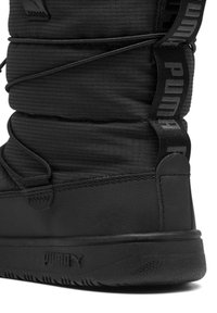 Botte noire isolante présentant un upper en tissu texturé, des lacets élastiques et un logo PUMA bien visible sur le côté et à l'arrière du talon.