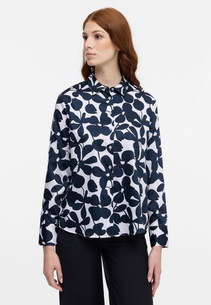 Langärmlige Bluse mit einem maritimen Blumenmuster auf weißem Hintergrund, aus leichtem Stoff mit Knopfleiste und Kragen.