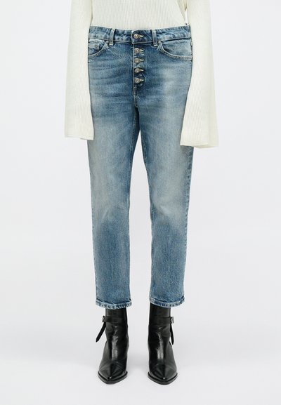 Lysblå, højtaljede jeans med knaplukning, lige ben og let falmede, parret med sorte spidse ankelstøvler.
