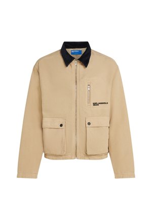 Beige jacket with a black corduroy collar, featuring a front zipper, two flap pockets, and one zippered chest pocket. Text logo on front.