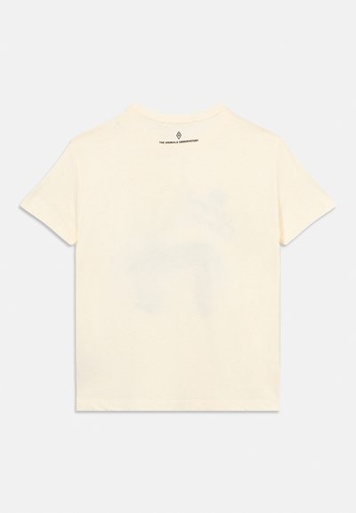 Μπεζ κοντομάνικη μπλούζα απλωμένη επίπεδα με μικρό μαύρο κείμενο και λογότυπο κοντά στον γιακά που γράφει «The Animals Observatory».