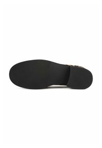 Semelle de chaussure à fond plat en caoutchouc noir, avec un motif de grip texturé et un design simple avec un talon légèrement courbé.